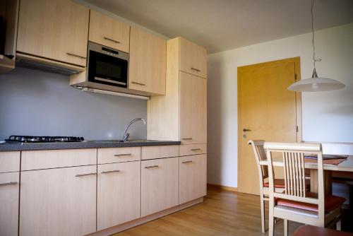 拉纳喀什塔霍芙公寓的带木制橱柜和桌子的厨房以及带水槽的厨房。