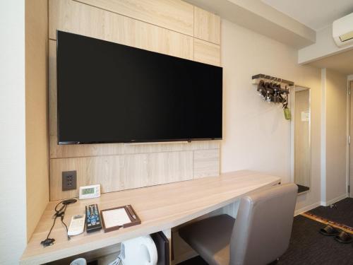 高山高山飞驒超级酒店的一间设有一张桌子的房间,墙上有一台电视机