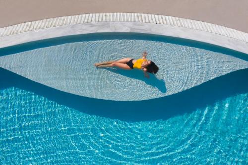 费拉Lilium Hotel Santorini的躺在游泳池冲浪板上的女人
