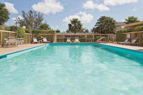 西棕榈滩西棕榈滩 - 佛罗里达收费公路拉金塔酒店的一个带椅子和围栏的大型游泳池