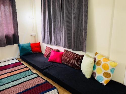 素可泰Baan Mae Somkid Homestay的窗户前的沙发上摆放着色彩缤纷的枕头