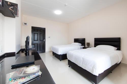 Pluak DaengJJ Residence的一间卧室配有两张床和一张书桌及电视