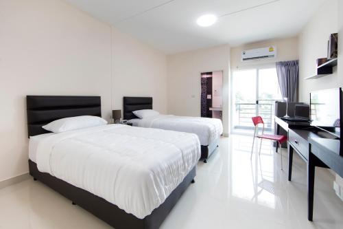 Pluak DaengJJ Residence的一间卧室配有两张床和一张书桌及电视