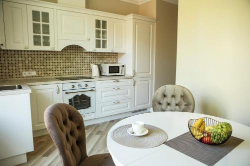 克莱佩达Old Town River Apartments的厨房配有白色的桌椅和一张带一碗水果的桌子。