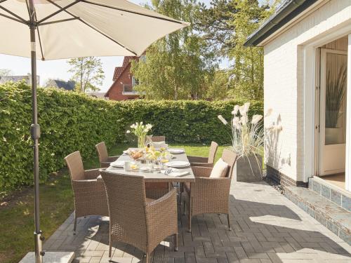 蒂门多弗施特兰德Techts Sommerhaus的庭院内桌椅和遮阳伞