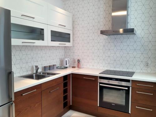 比亚韦斯托克Emerald Apartament的厨房配有木制橱柜、水槽和炉灶。