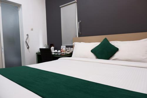 库塔Ara Inn Bed And Breakfast by ecommerceloka的卧室配有一张带绿色枕头的大型白色床