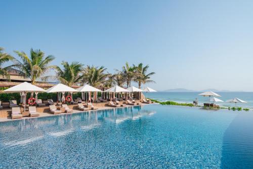 金兰金兰融合度假酒店 - Spa全包的一个带椅子和遮阳伞的游泳池以及大海