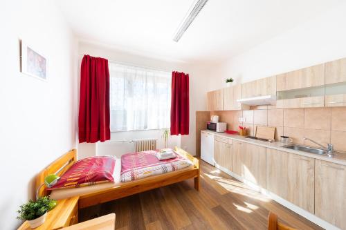 布拉格贝尼斯旅馆的一间设有床铺的客房和一间带红色窗帘的厨房