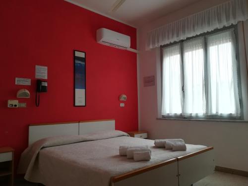 里米尼皮加勒酒店的红色卧室配有带2条毛巾的床
