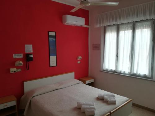 里米尼皮加勒酒店的一间卧室设有红色的墙壁和一张带两条毛巾的床