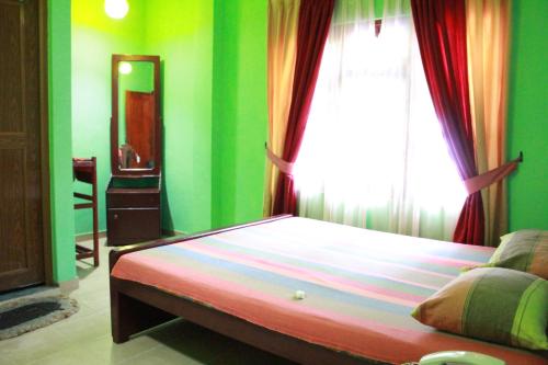 WarakapolaWijaya Tourist INN的一间卧室设有一张带绿色墙壁和窗户的床。