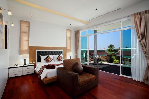 卡塔海滩Kata Sea View Villas的一间卧室配有一张床、一把椅子和一个大窗户