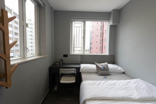 香港Studio Stay的客房设有两张床、一张书桌和两个窗户。