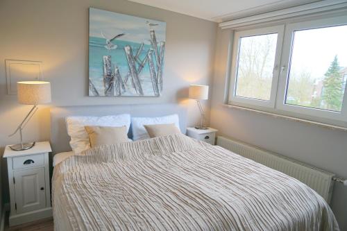 克伦胡森Haus Ruh di ut Wohnung LUV的一间卧室配有一张带条纹毯子的床和两个窗户