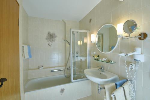 巴特恩多夫爱特布如娜酒店的带淋浴、盥洗盆和浴缸的浴室