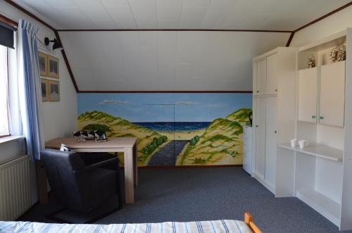 东卡佩勒De strandkamer的一间设有书桌的客房,墙上挂有绘画作品