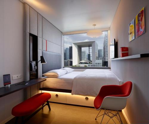楠泰尔巴黎拉德芳斯世民酒店 的一间卧室配有一张大床和一张红色椅子