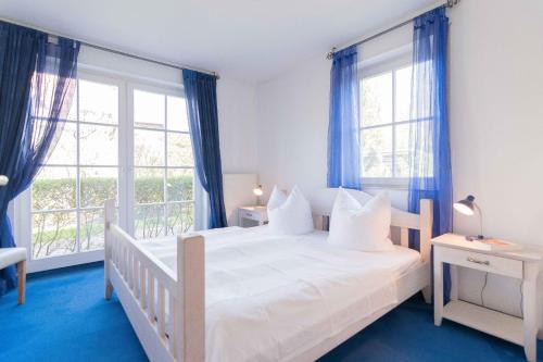 欧巴德伍斯图Strandoase Typ STO-A STRANDOASE Whg. SO6的卧室配有白色床、蓝色地板和窗户。
