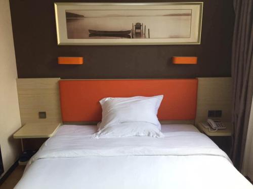 灌云7天优品连云港灌云南京西路和盛广场店的一间卧室配有一张带橙色床头板的床