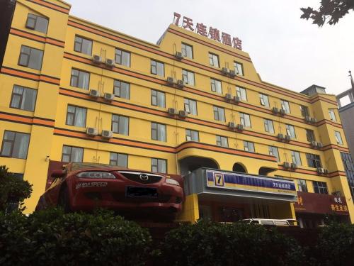 洛阳7天酒店·洛阳新安店的一座黄色的建筑,前面有一辆汽车