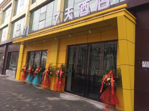 乌鲁木齐7天酒店·乌鲁木齐喀什东路师范大学店的黄色的建筑,有一群身着五颜六色衣着的女人