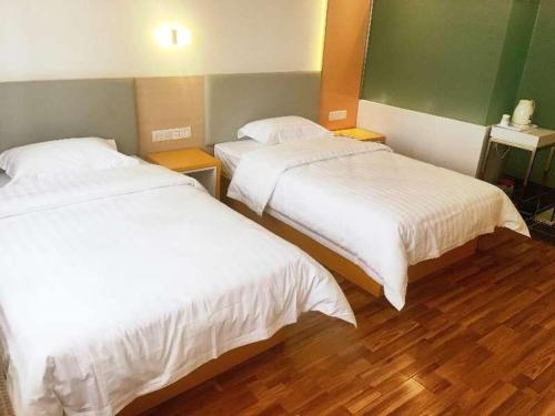 乌鲁木齐7天酒店·乌鲁木齐喀什东路师范大学店的铺有木地板的客房内的两张床