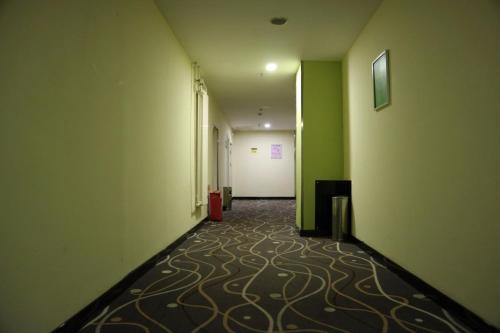 长春7天酒店长春红旗街大学城南湖广场店的一条空的走廊,有绿色的墙壁,地板铺有地毯