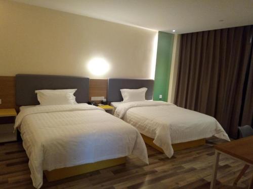 Yaopu7天酒店·孝义人民医院店的酒店客房,配有两张带白色床单的床