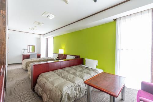广岛广岛和平公园经济型酒店的一间卧室设有两张床和绿色的墙壁