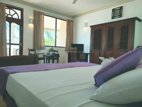 本托塔Oasey Ayurveda Hotel的卧室配有一张带紫色枕头的大型白色床。