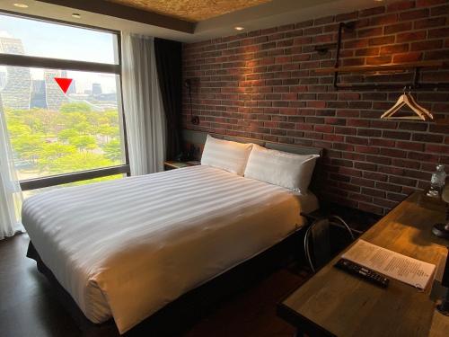 高雄城市商旅 - 高雄驳二馆的一间卧室设有一张大床和砖墙