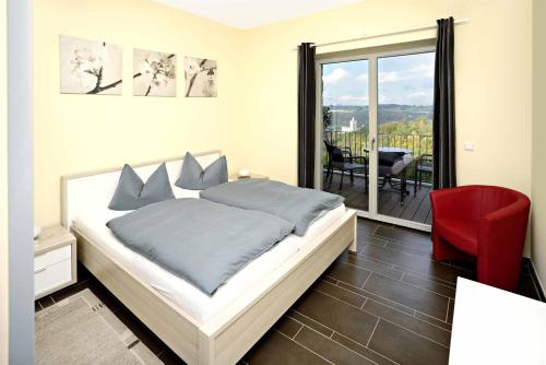 萨勒河畔瑙姆堡Hotel und Restaurant Rittergut Kreipitzsch的一间卧室配有一张床和一张红色椅子,并设有一个阳台