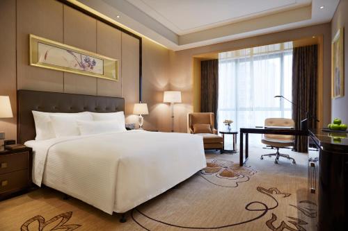 北京北京万达嘉华酒店的卧室配有一张白色大床和一张书桌