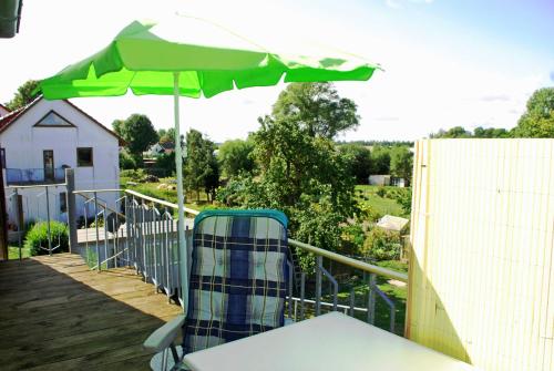 PatzigFerienwohnung Familie Schoenemann的甲板上的绿色遮阳伞和椅子