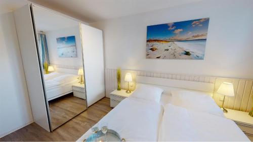 佩尔泽哈肯Villa Meeresrauschen Meerblick 6a的一间白色卧室,配有两张床和镜子