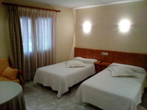 格劳斯Hostal Lopez的酒店客房,配有两张床和椅子