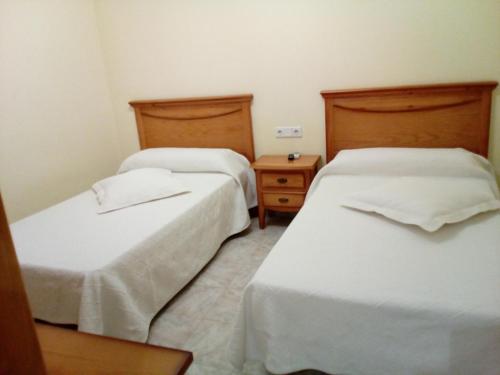 格劳斯Hostal Lopez的配有白色床单的酒店客房内的两张床