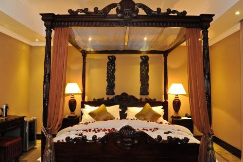 布隆方丹安踏博加酒店 的卧室配有带枕头的大型木制天蓬床