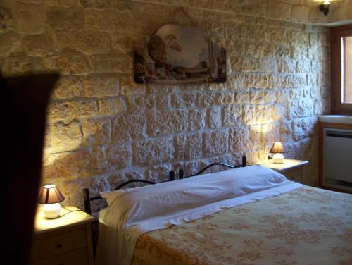法萨诺Agriturismo Locanda Ventura的一间卧室设有石墙、一张床和两盏灯。