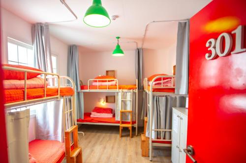 济州市SUM济州机场旅馆的宿舍间设有双层床和红色门。