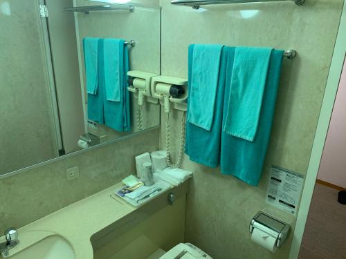 铃鹿市铃鹿斯托利亚酒店的浴室提供蓝色毛巾、水槽和镜子