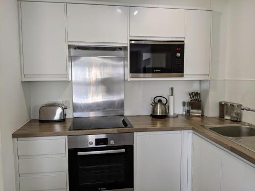 海维康Saffron Court by Wycombe Apartments - Apt 06的厨房配有白色橱柜和黑烤箱。