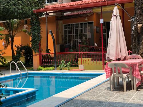 TamazunchaleHotel Paraiso Huasteco的房屋旁的游泳池配有桌子和遮阳伞