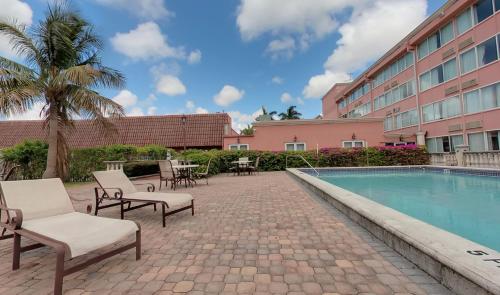 迈阿密Miami Gardens Inn & Suites的一座带游泳池和椅子的酒店和一座建筑