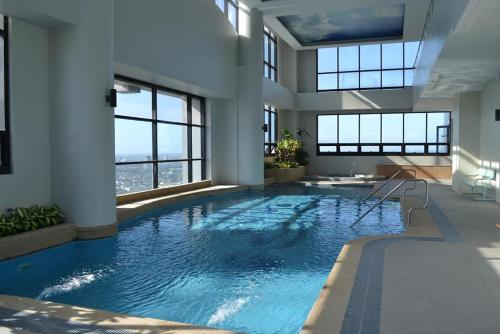 马尼拉BSA双子塔酒店的一座大型游泳池,位于一座带窗户的建筑内
