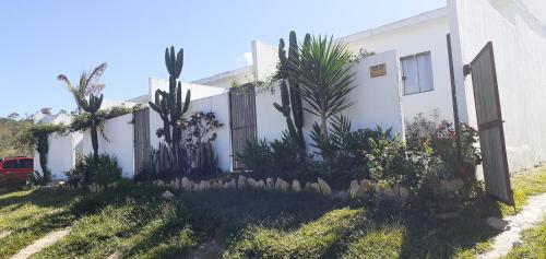 戈亚斯州上帕莱索A Taberna - chalés的一座白色的房子,里面种有植物和栅栏
