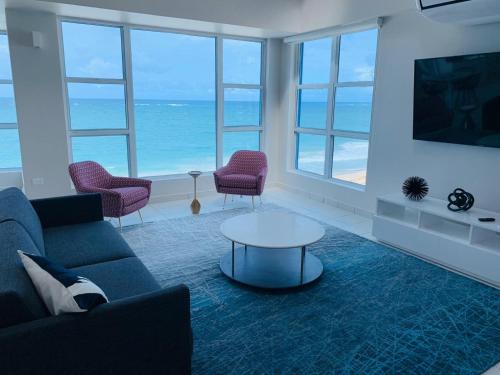 圣胡安The Tryst Beachfront Hotel的一间带沙发和椅子的客厅,享有海景。