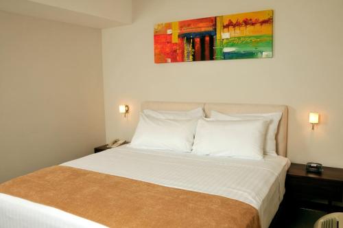 埃斯特利Hotel Hex Estelí的卧室配有白色床,上面有绘画作品