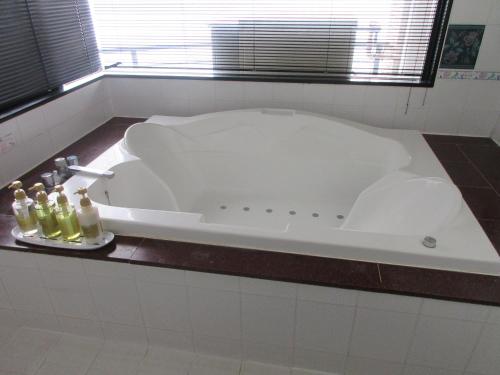 鹿儿岛ウォーターゲート鹿児島的浴室内的白色浴缸,在柜台上装有瓶子